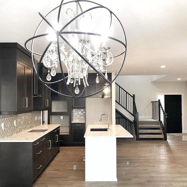 A kitchen with a large chandelier and wooden floors.